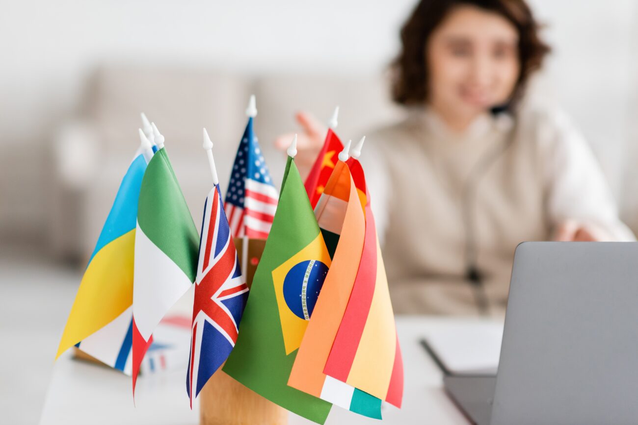 Selective,Focus,Of,Various,International,Flags,Near,Blurred,Laptop,And